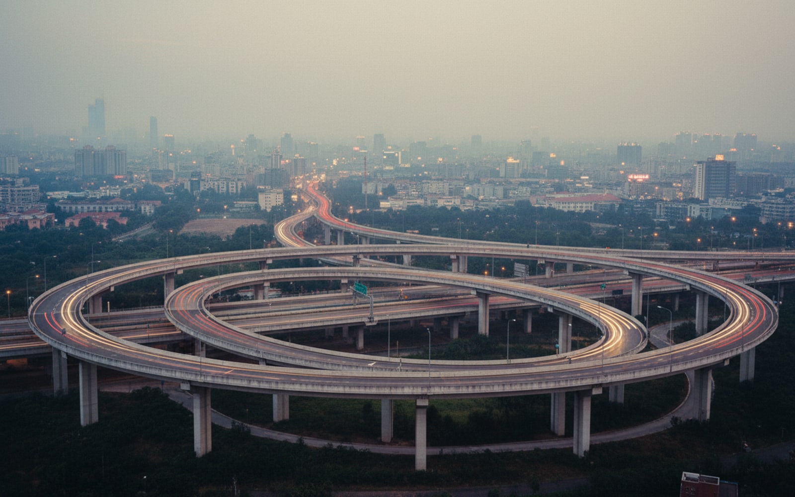 Elevated view of a multi-level road interchange at dusk with faint light trails